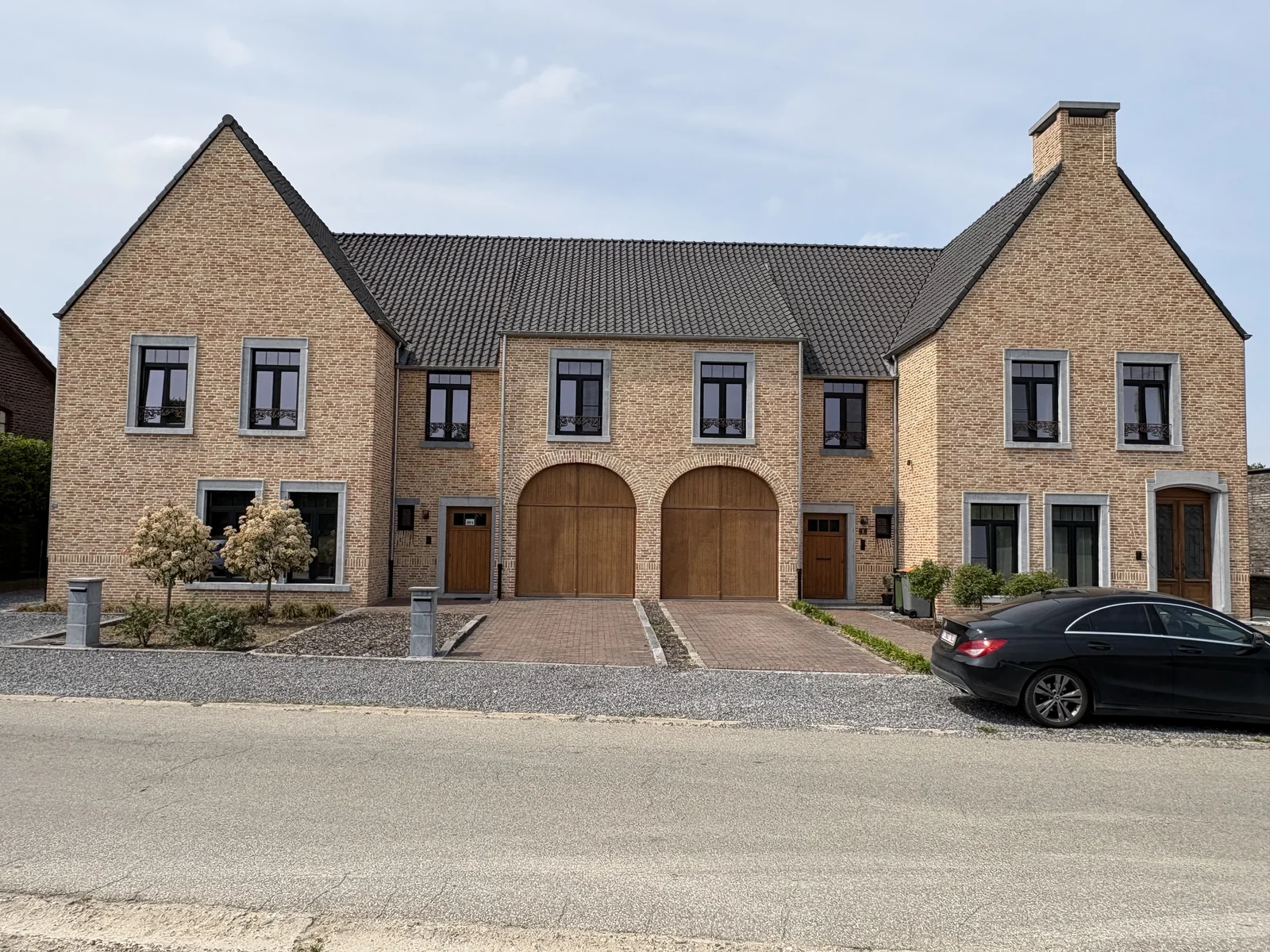 Twee landelijke woningen in Maasmechelen met bakstenen gevel en boog-garagepoorten